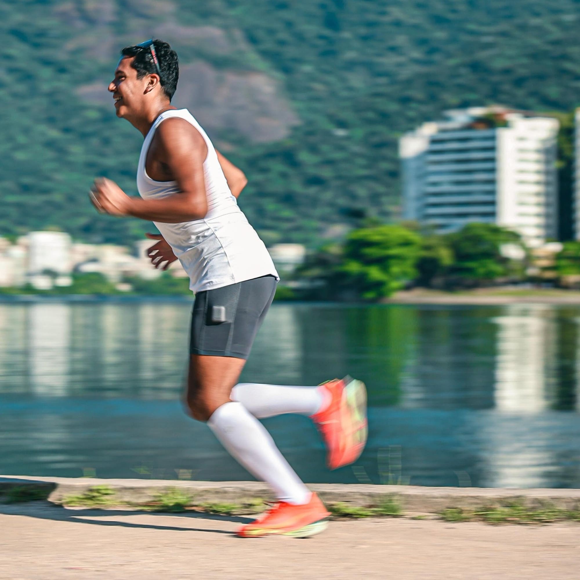 Man joggar utomhus längs en sjöpromenad iförd vita kompressionsstrumpor