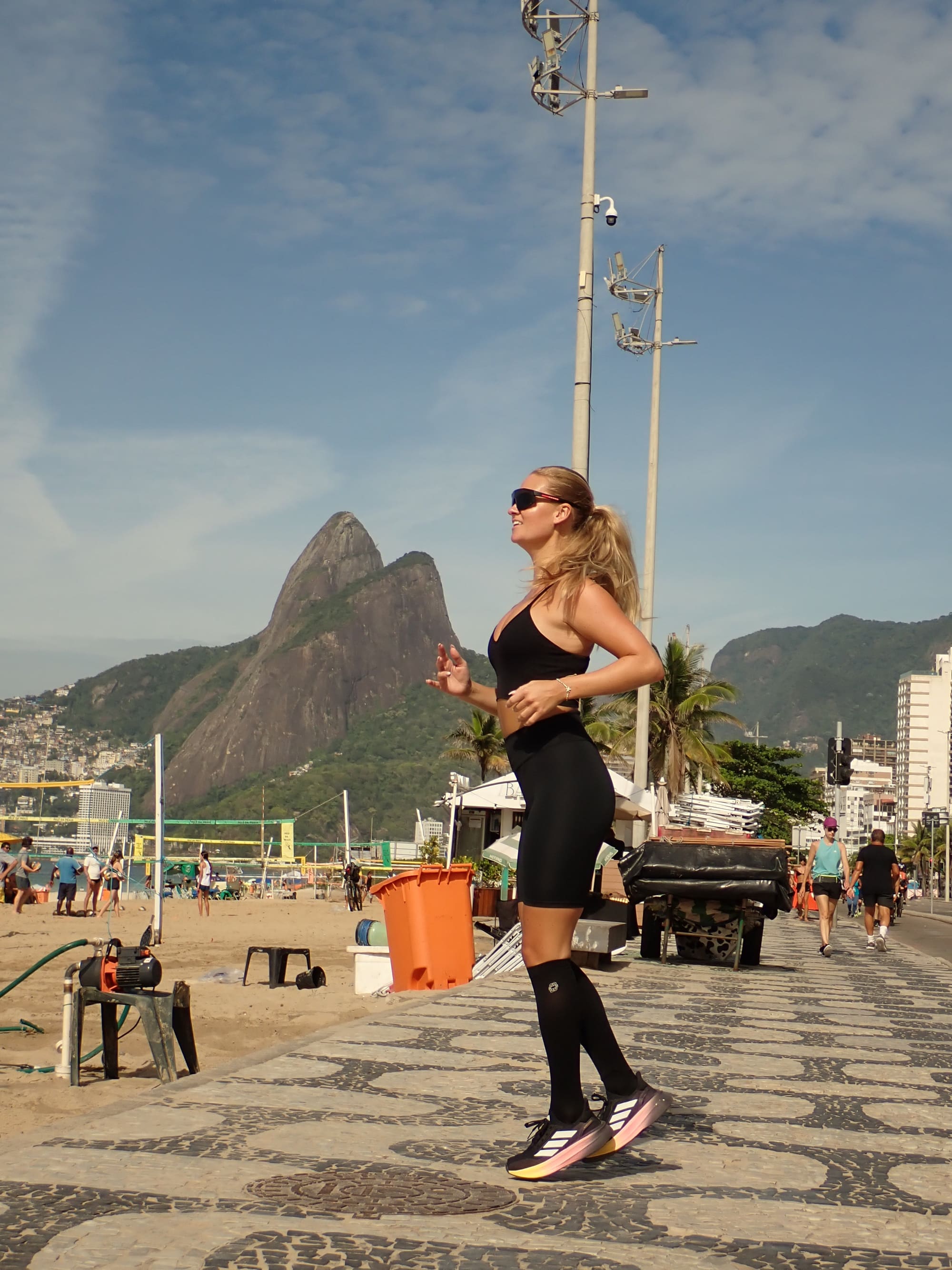 Kvinna joggar längs en strandpromenad i Rio de Janeiro iförd höga stödstrumpor